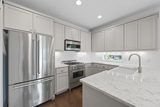 a kitchen with stainless steel appliances granite countertop a sink a stove a refrigerator with white cabinets