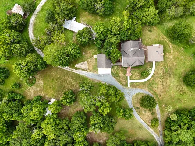 an aerial view of residential house with outdoor space and trees all around