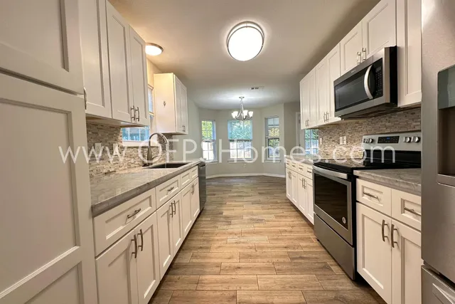 a large kitchen with stainless steel appliances lots of counter space and a sink