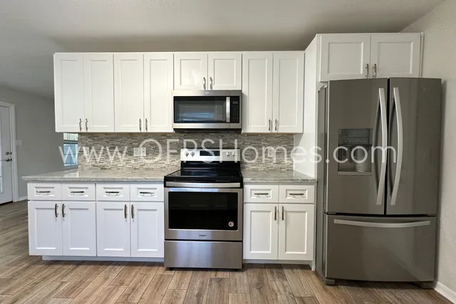 a kitchen with white cabinets and stainless steel appliances