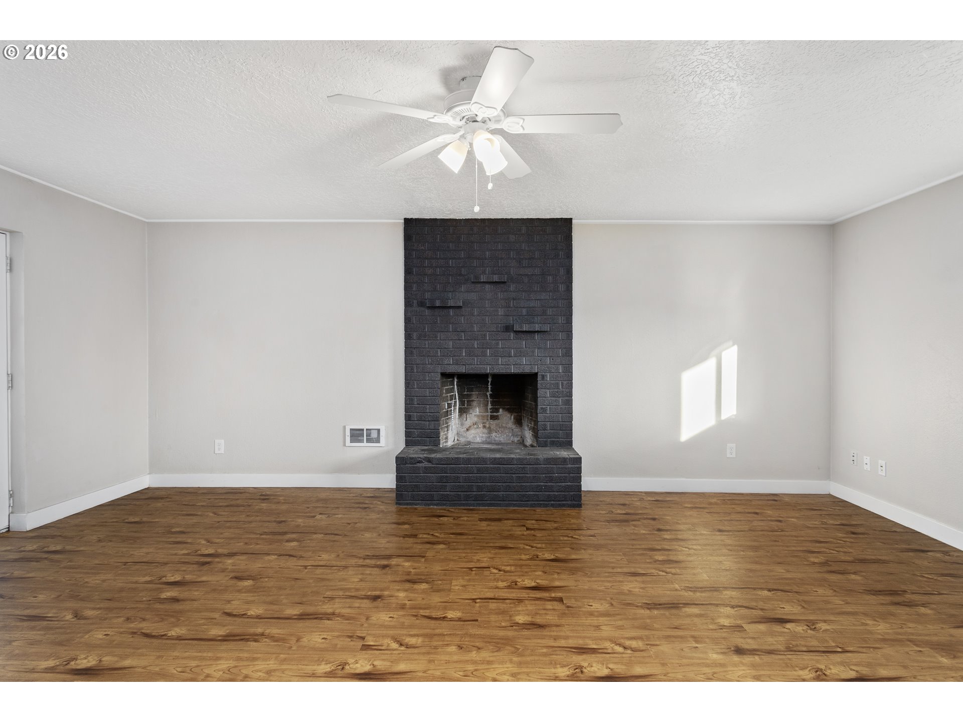 8705 Southeast Pardee Street Portland, OR 97266 - Photo 11 of 32 a view of an empty room with wooden floor and a fireplace