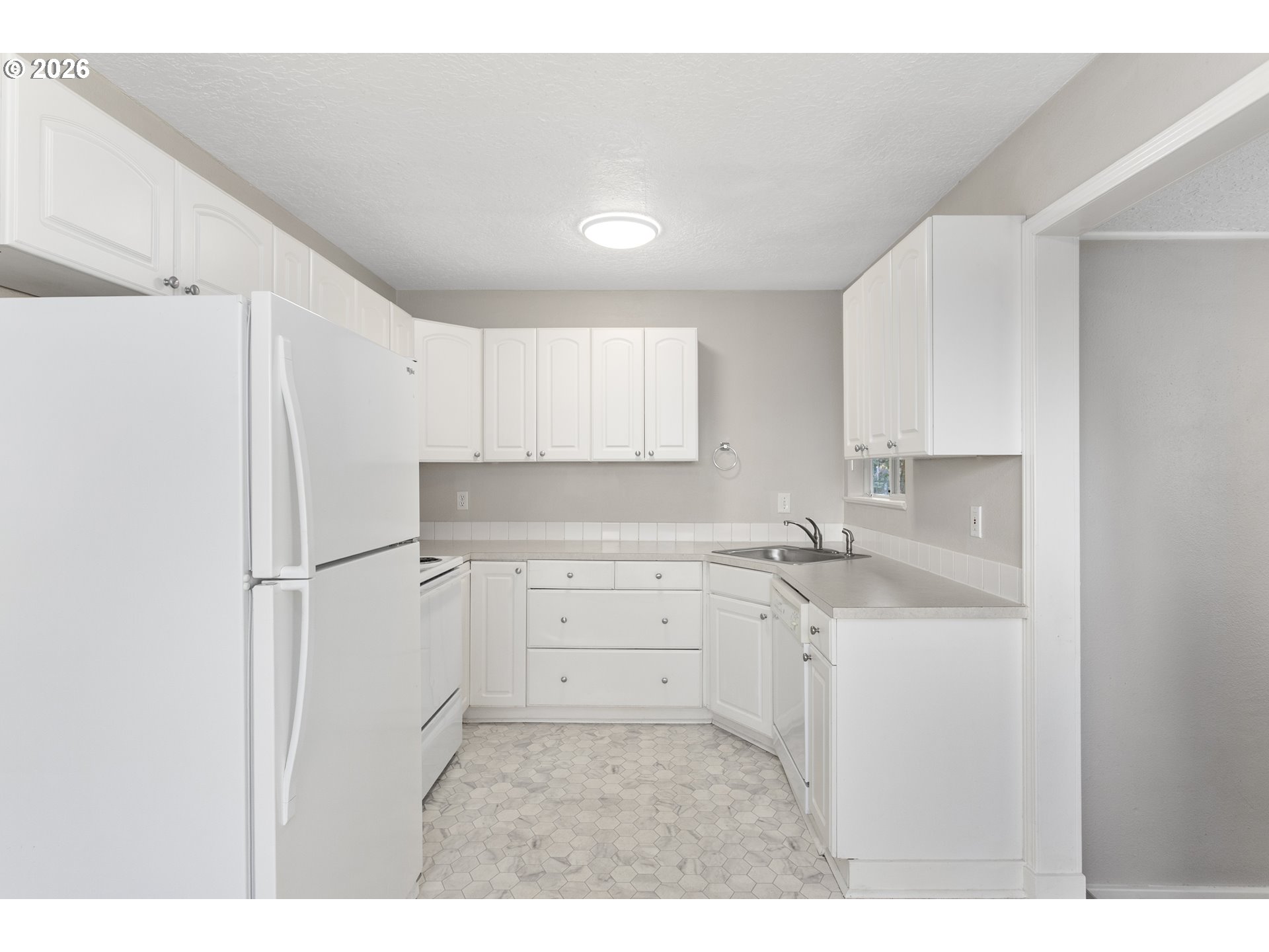 8705 Southeast Pardee Street Portland, OR 97266 - Photo 7 of 32 a kitchen with a sink a stove a refrigerator and white cabinets