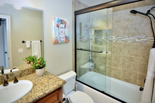 a bathroom with a granite countertop sink a toilet and shower
