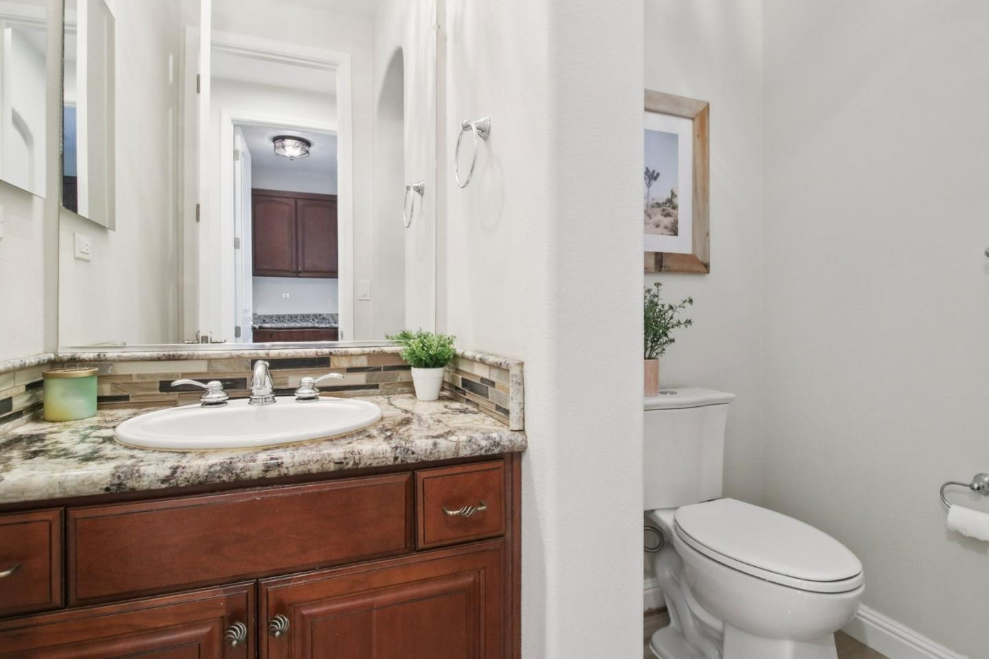 7670 MacKenzie Way Gilroy, CA 95020 - Photo 26 of 70 a bathroom with a granite countertop sink a toilet and a mirror