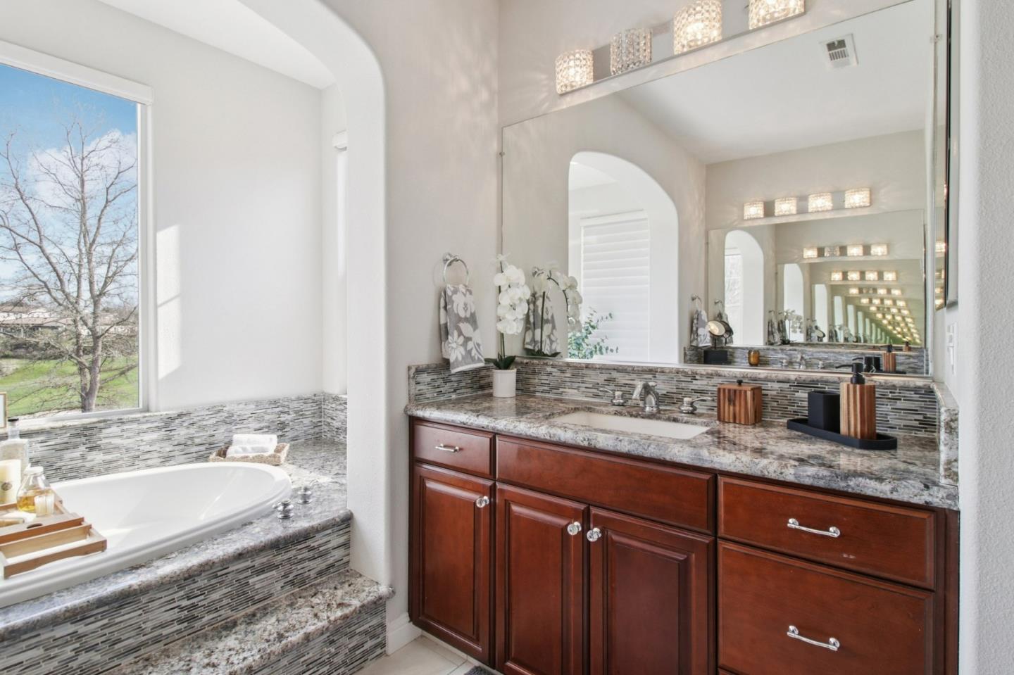 7670 MacKenzie Way Gilroy, CA 95020 - Photo 50 of 70 a bathroom with a granite countertop tub a double vanity sink and a large mirror