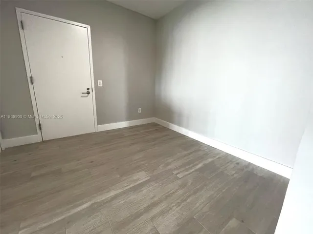 an empty room with wooden floor and mirror