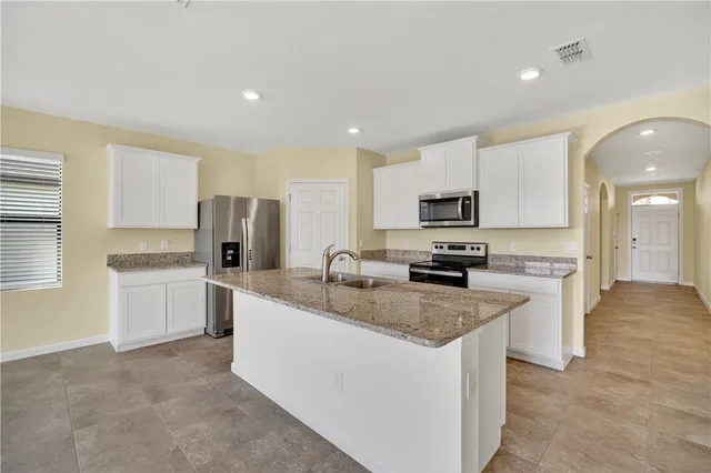 a large kitchen with a stove top oven a sink dishwasher a refrigerator and white cabinets with wooden floor