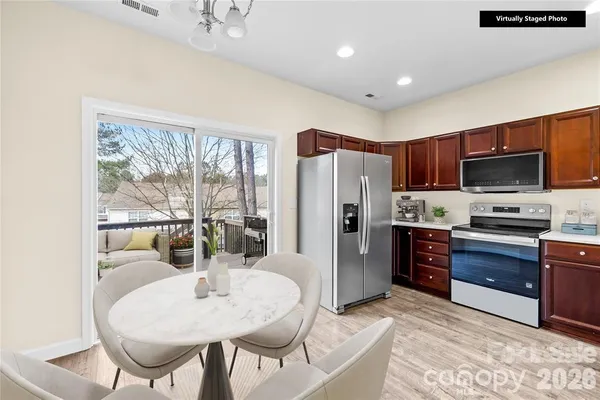 a kitchen with stainless steel appliances kitchen island granite countertop a refrigerator a stove top oven and a dining table with wooden floor