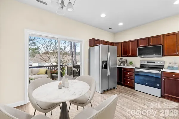 a kitchen with stainless steel appliances kitchen island granite countertop a refrigerator a stove top oven and a dining table with wooden floor