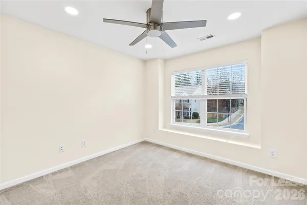 an empty room with a window and a ceiling fan