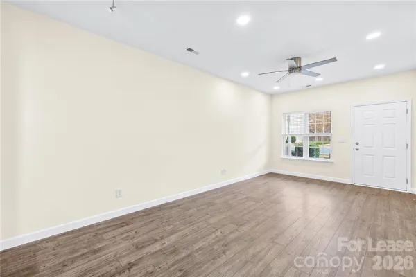 an empty room with wooden floor ceiling fan and windows