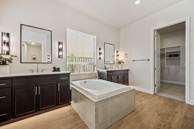a bathroom with a tub a sink and mirror