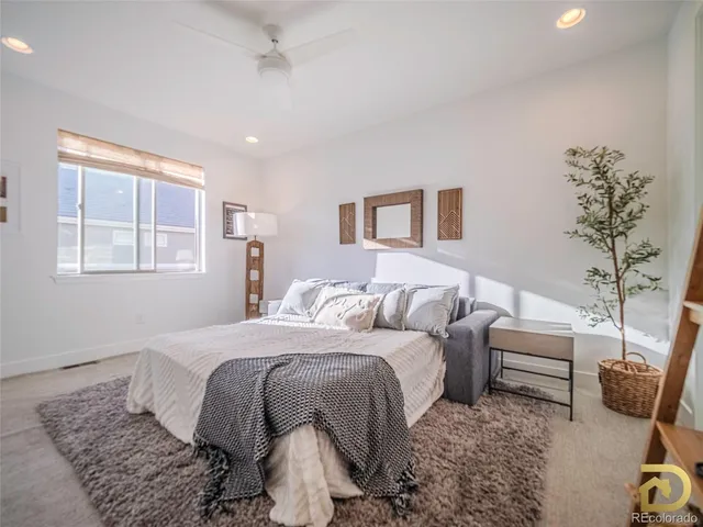 a bedroom with a bed a couch and potted plant in it