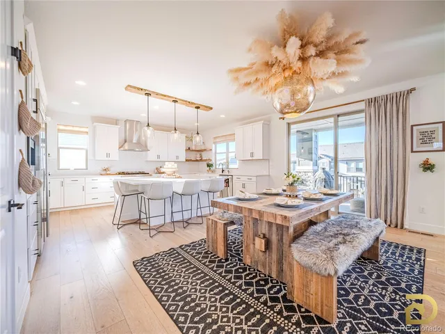 a open dining room with stainless steel appliances kitchen island granite countertop a stove refrigerator and a dining table with wooden floor