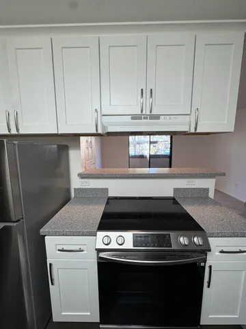 a view of a refrigerator in kitchen and an empty room