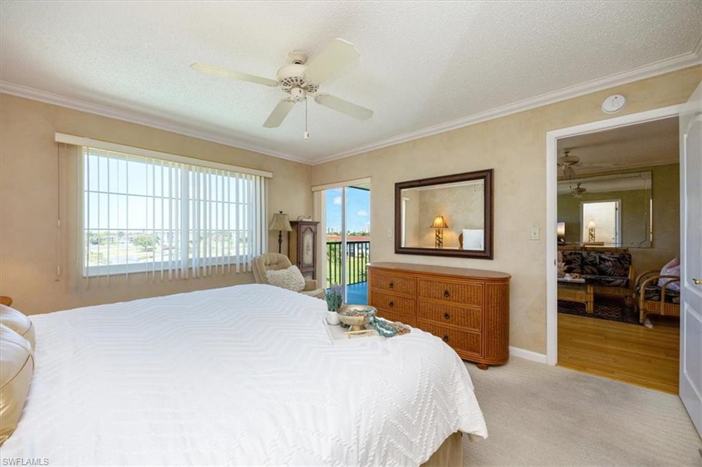 21 High Point Circle East, Unit 502 Naples, FL 34103 - Photo 14 of 24 a bedroom with a large bed and a chandelier