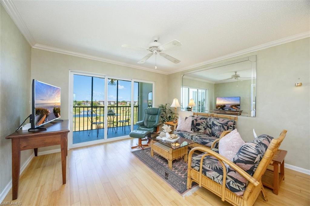 21 High Point Circle East, Unit 502 Naples, FL 34103 - Photo 7 of 24 a living room with furniture a flat screen tv and floor to ceiling window
