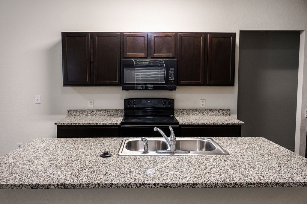 14915 Talus Road Manor, TX 78653 - Photo 5 of 20 Rich dark wood cabinetry pairs with granite countertops in this functional workspace.