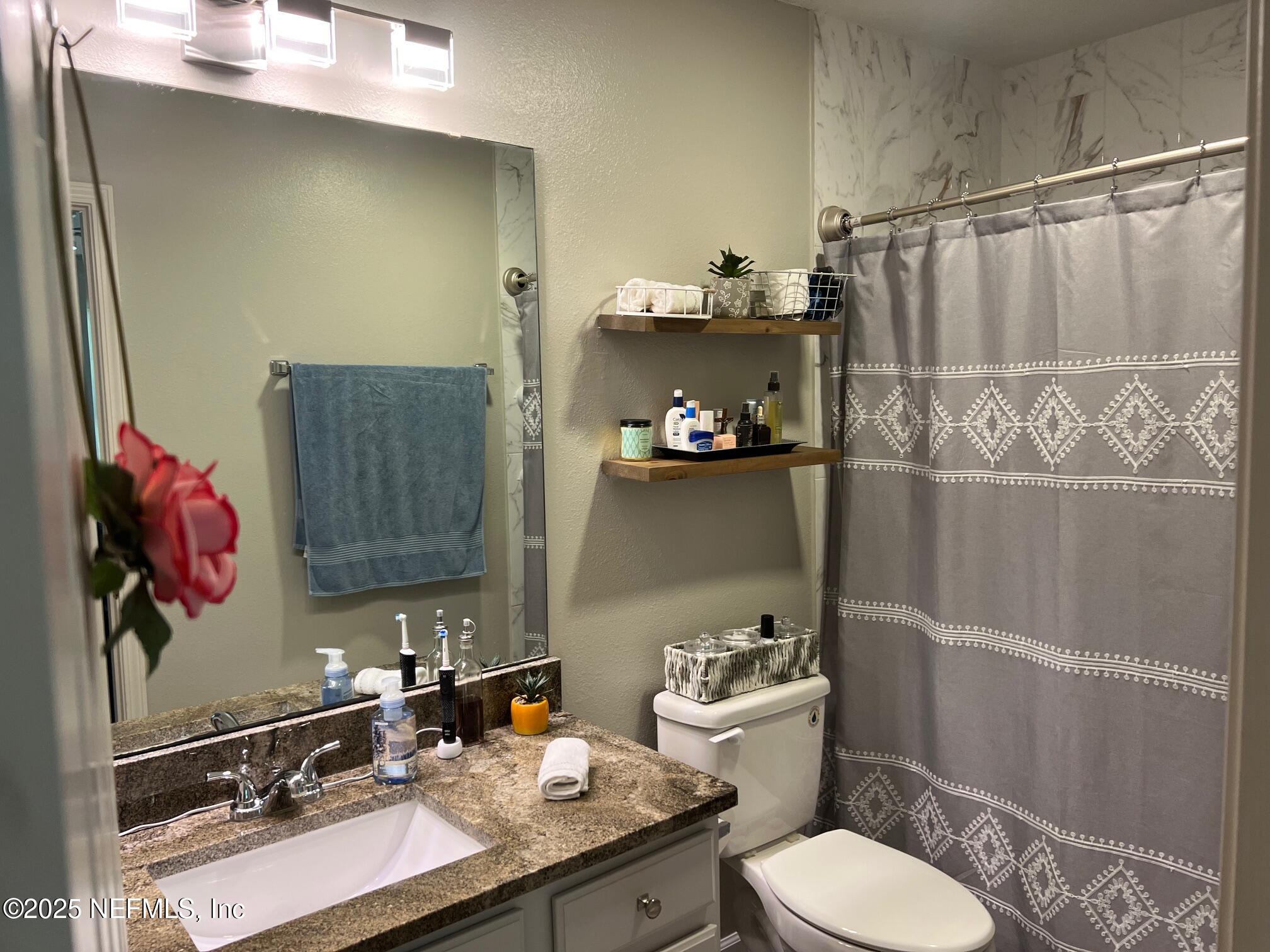 385 Scrub Jay Drive St. Augustine, FL 32092 - Photo 9 of 16 a bathroom with a granite countertop toilet sink and mirror