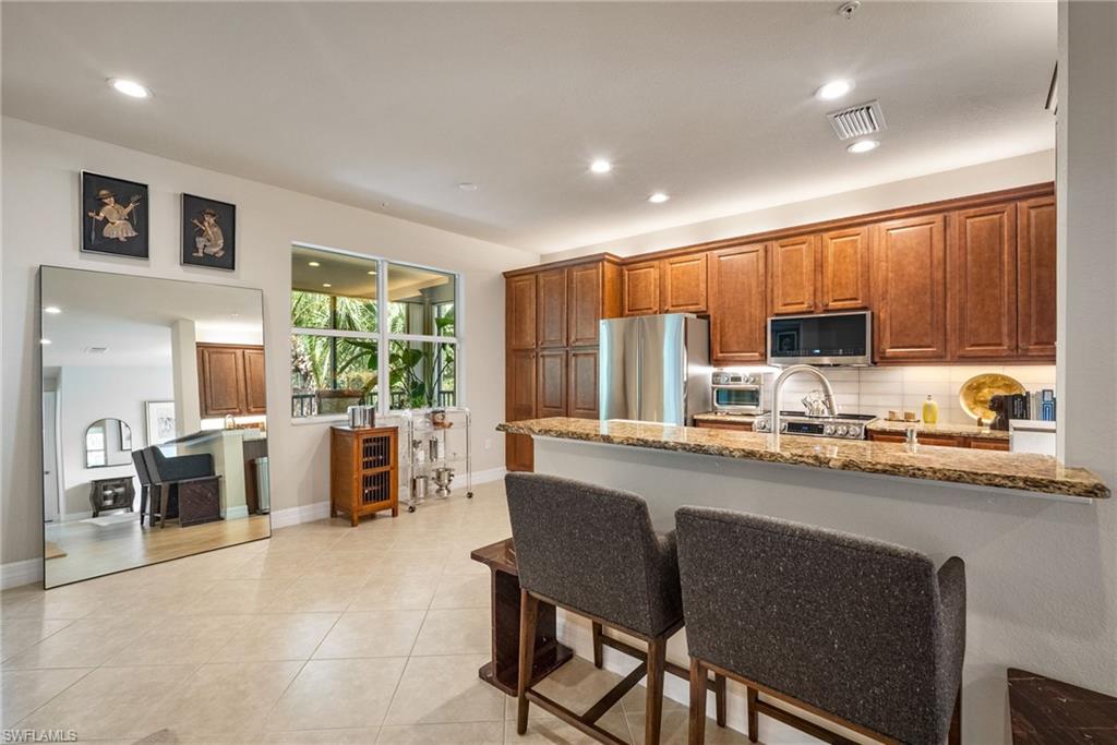 6510 Monterey Point, Unit 204 Naples, FL 34105 - Photo 6 of 48 a kitchen with stainless steel appliances granite countertop a stove top oven a sink dishwasher a dining table and chairs with wooden floor