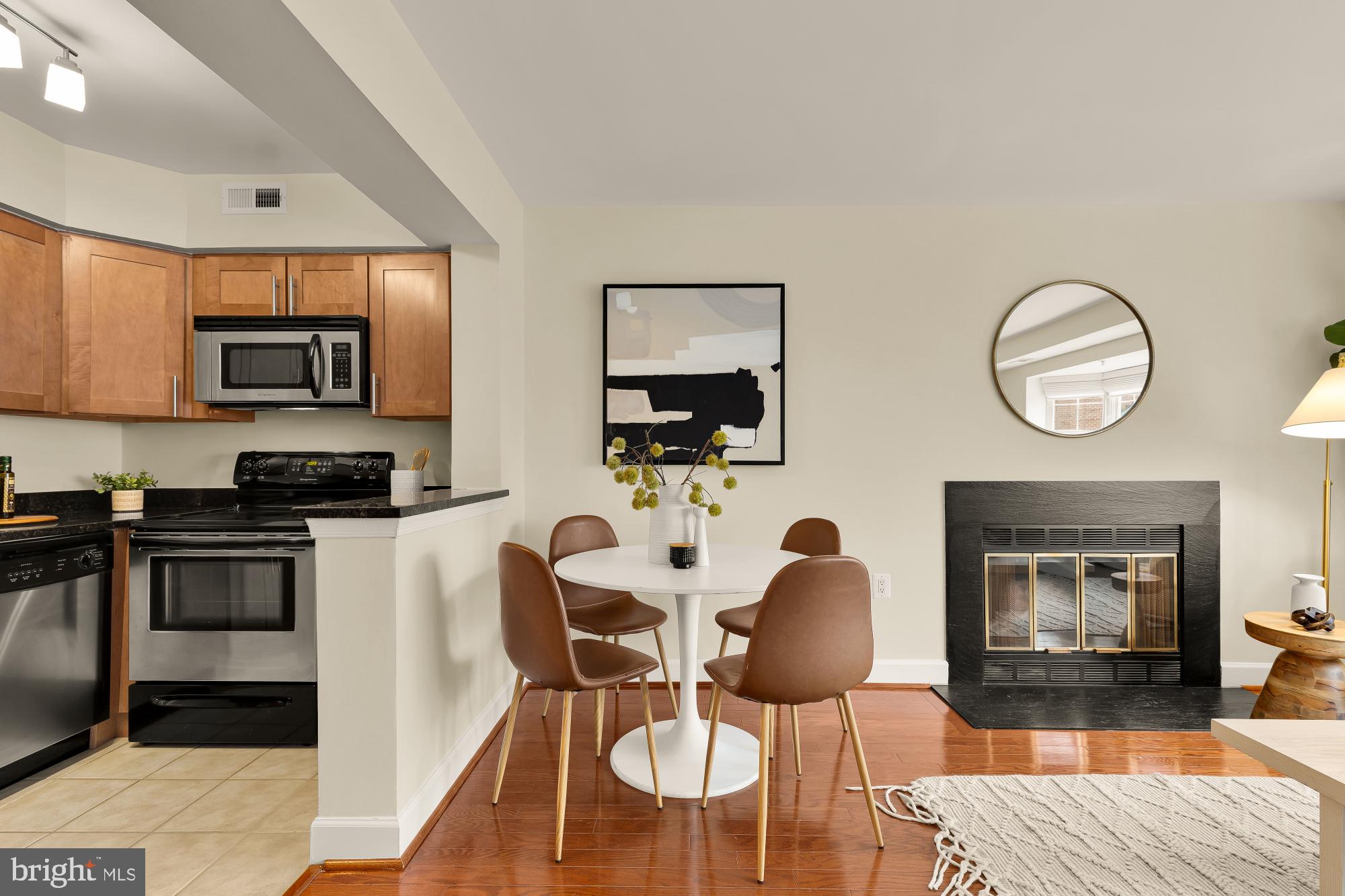 3804 Rodman Street Northwest, Unit 303 Washington, DC 20016 - Photo 15 of 33 a kitchen with stainless steel appliances granite countertop a stove a sink a microwave a dining table and chairs with wooden floor