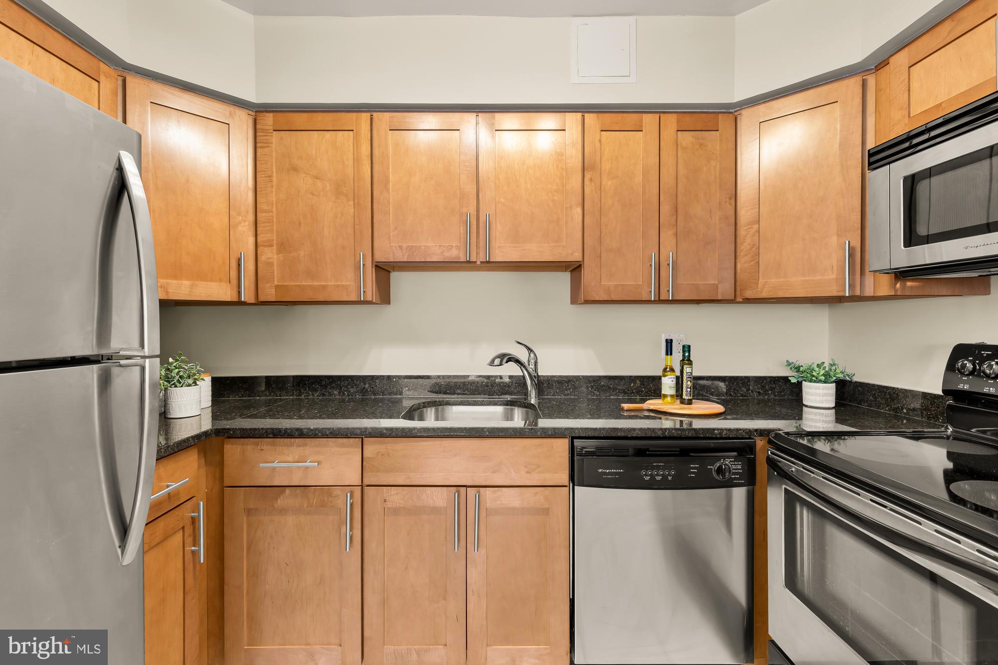 3804 Rodman Street Northwest, Unit 303 Washington, DC 20016 - Photo 16 of 32 a kitchen with stainless steel appliances granite countertop a sink stove and microwave