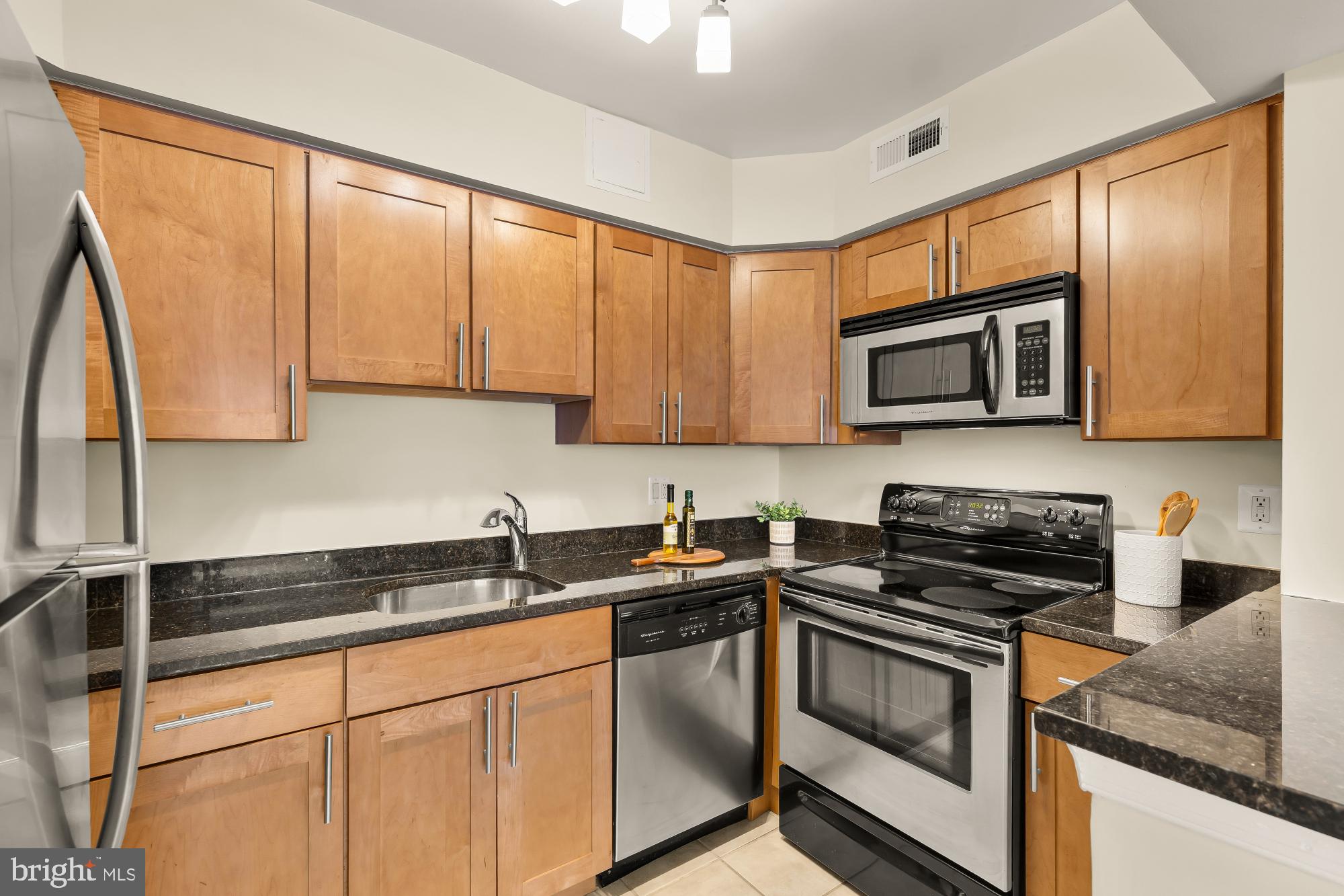 3804 Rodman Street Northwest, Unit 303 Washington, DC 20016 - Photo 16 of 33 a kitchen with stainless steel appliances granite countertop white cabinets stove a sink and dishwasher