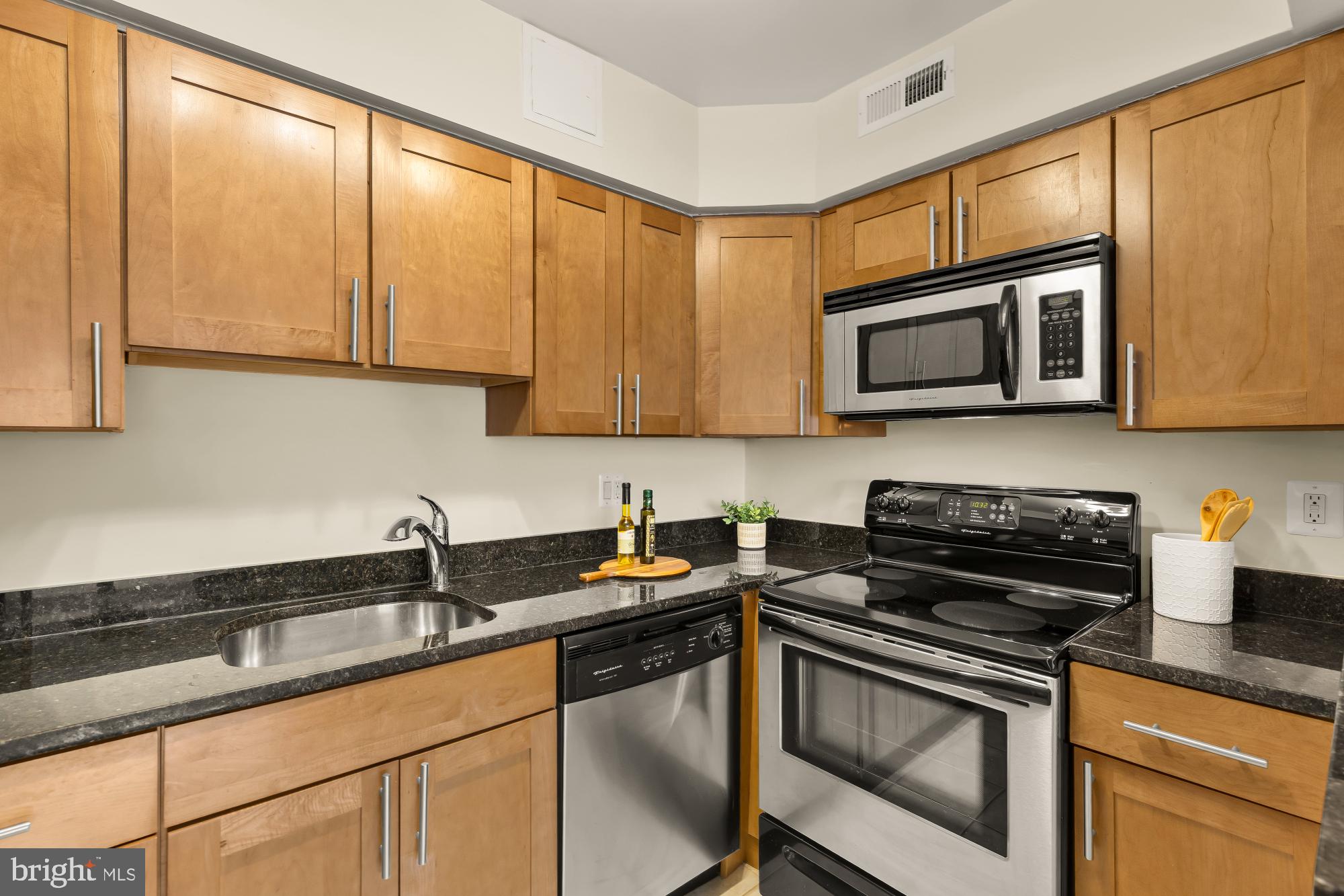 3804 Rodman Street Northwest, Unit 303 Washington, DC 20016 - Photo 18 of 33 a kitchen with stainless steel appliances granite countertop a sink a stove a microwave and cabinets