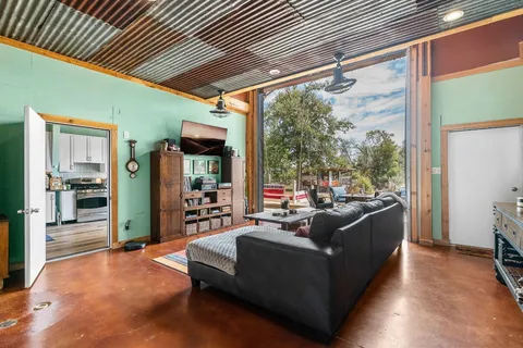 a living room with furniture a floor to ceiling window and wooden floor