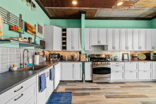 a kitchen with stainless steel appliances kitchen island granite countertop a sink a stove and cabinets