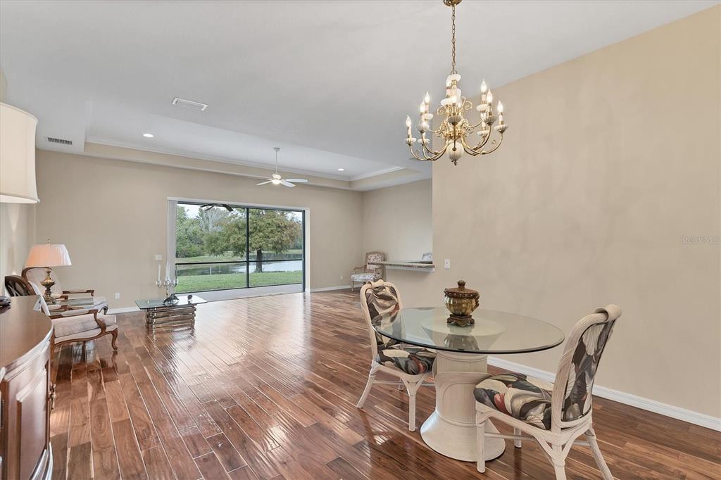 7909 Rio Bella Place Bradenton, FL 34201 - Photo 5 of 38 a dining room with furniture a chandelier and wooden floor