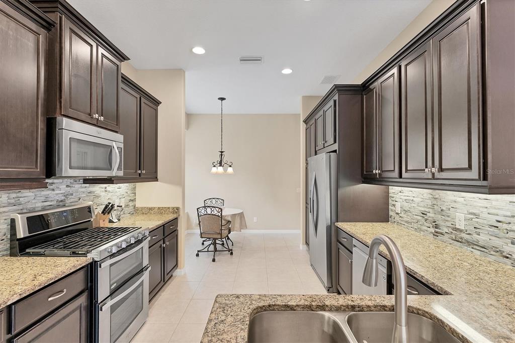 7909 Rio Bella Place Bradenton, FL 34201 - Photo 8 of 34 a kitchen with granite countertop a sink appliances cabinets and furniture
