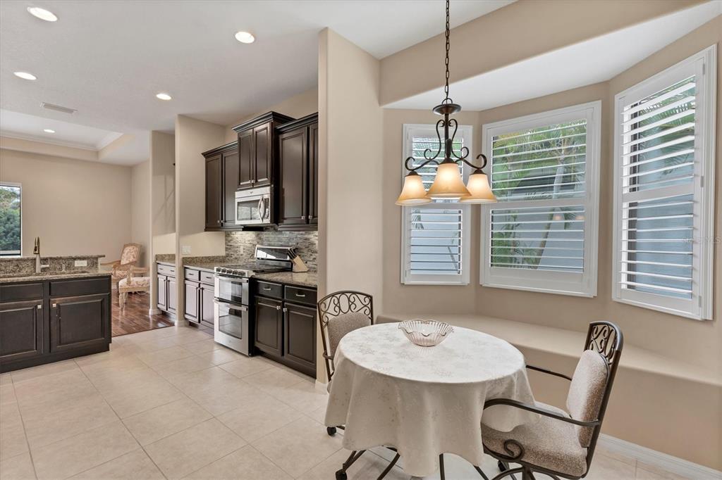 7909 Rio Bella Place Bradenton, FL 34201 - Photo 10 of 38 a kitchen with stainless steel appliances granite countertop a stove top oven a sink a dining table and chairs