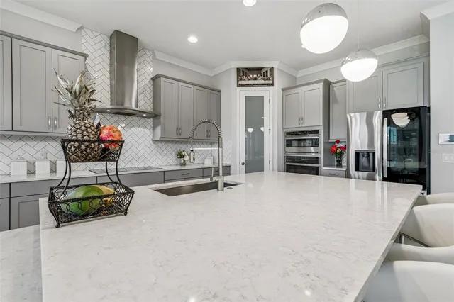 a large white kitchen with lots of counter space a sink appliances and cabinets