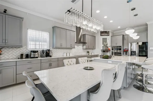 a kitchen with stainless steel appliances kitchen island a table chairs sink and cabinets