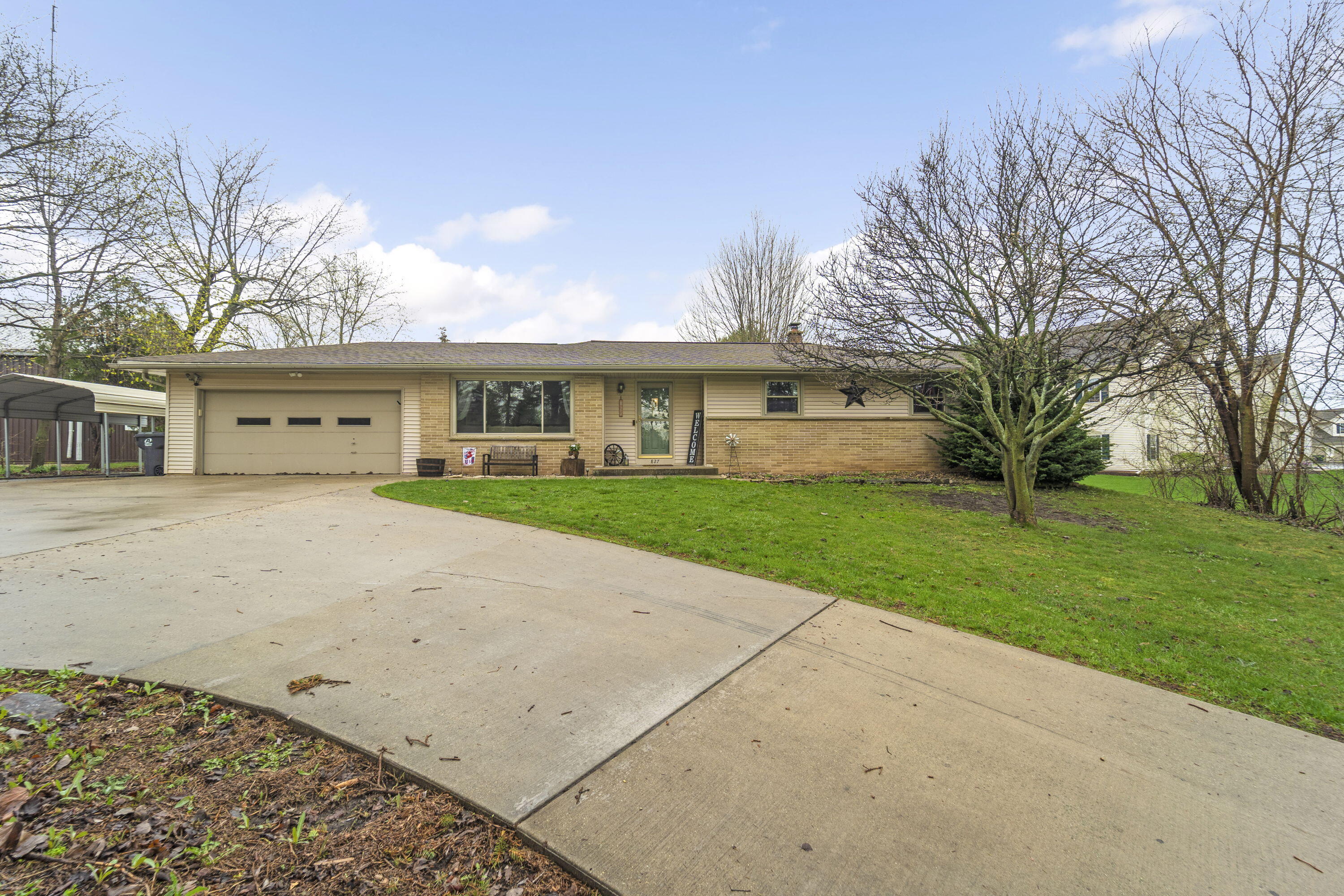 Welcoming ranch with attached garage, mature trees, and spacious driveway offering great curb appeal.