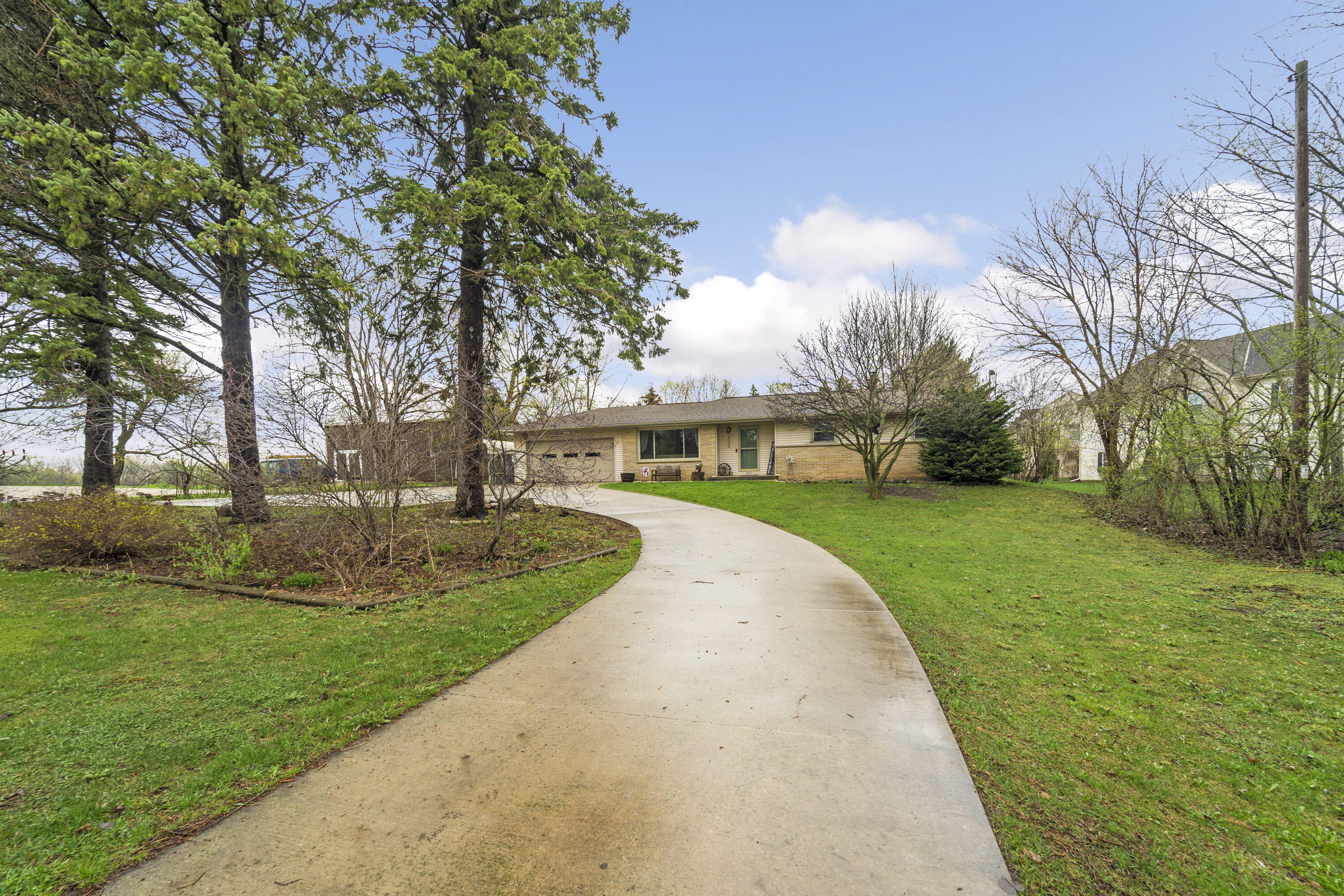 827 South Fancher Road Mount Pleasant, WI 53406 - Photo 2 of 26 Curved driveway creates a beautiful approach, framed by mature trees and a spacious front yard.