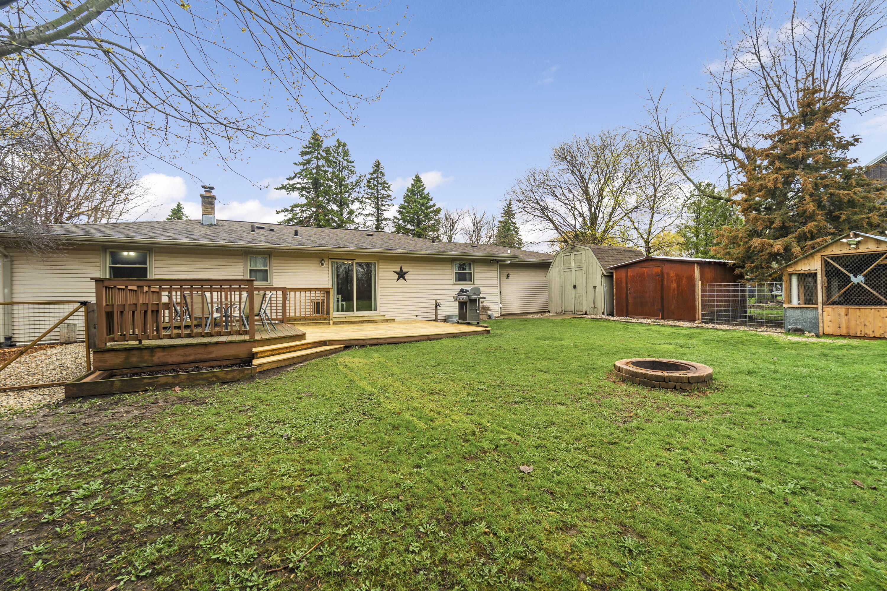 827 South Fancher Road Mount Pleasant, WI 53406 - Photo 21 of 26 Backyard with deck, fire pit area, and multiple structures offering flexible outdoor use.