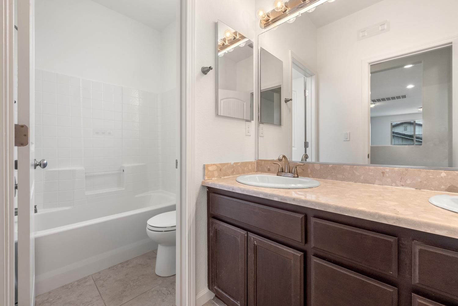 1513 Rock Spring Avenue Manteca, CA 95337 - Photo 39 of 56 a bathroom with a granite countertop sink a toilet and shower