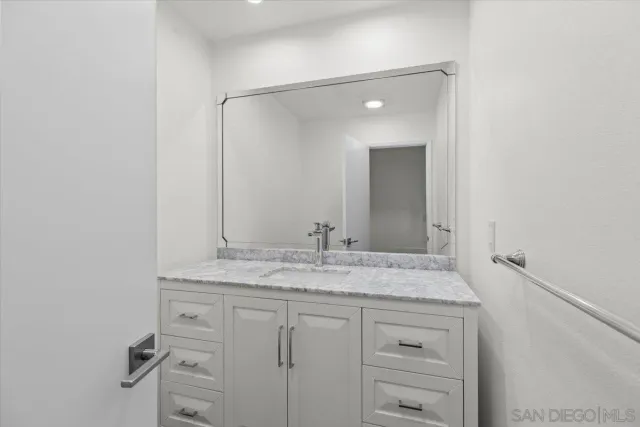 a bathroom with a granite countertop sink and a mirror