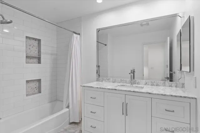 a bathroom with a granite countertop sink mirror and a bathtub
