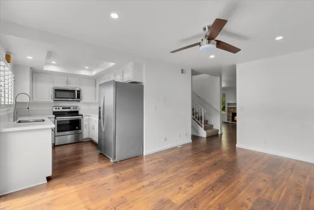 a view of a kitchen with a sink refrigerator and wooden floor
