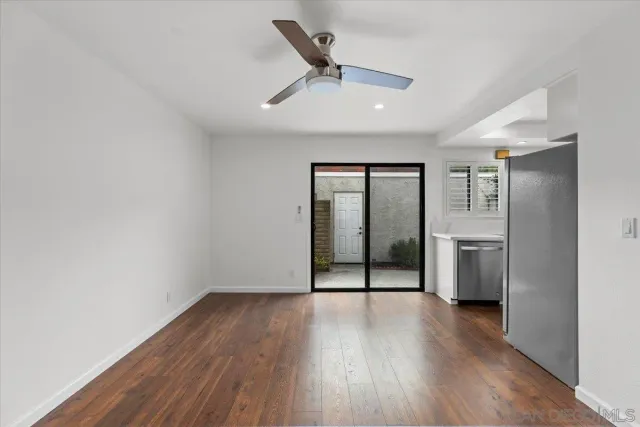 an empty room with wooden floor and a ceiling fan