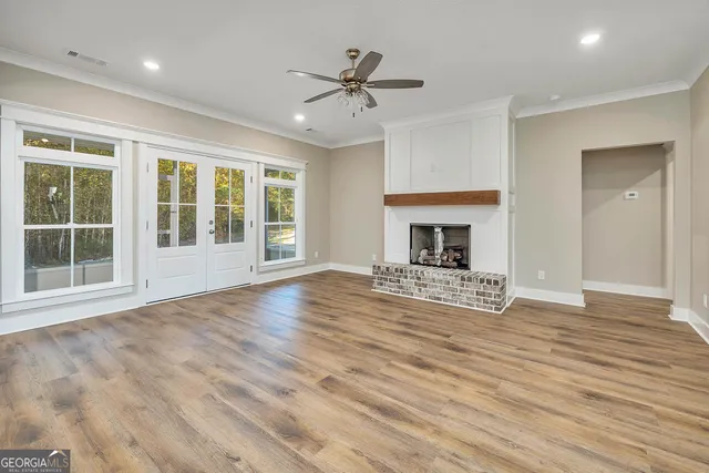 a view of an empty room with wooden floor fireplace and a window