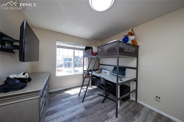 7511 Coffee Road Peyton, CO 80831 - Photo 31 of 38 Bedroom with wood finished floors, baseboards, and an office area