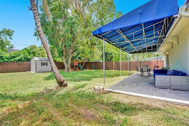 a view of a backyard with a barn and a large tree