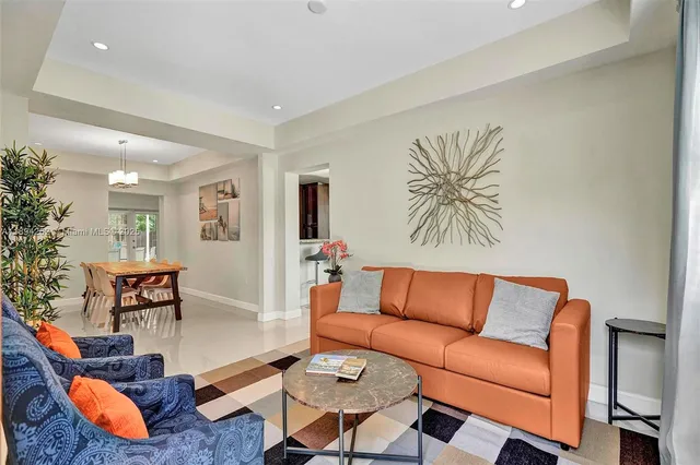 a blue couch sitting in a living room with furniture and a potted plant
