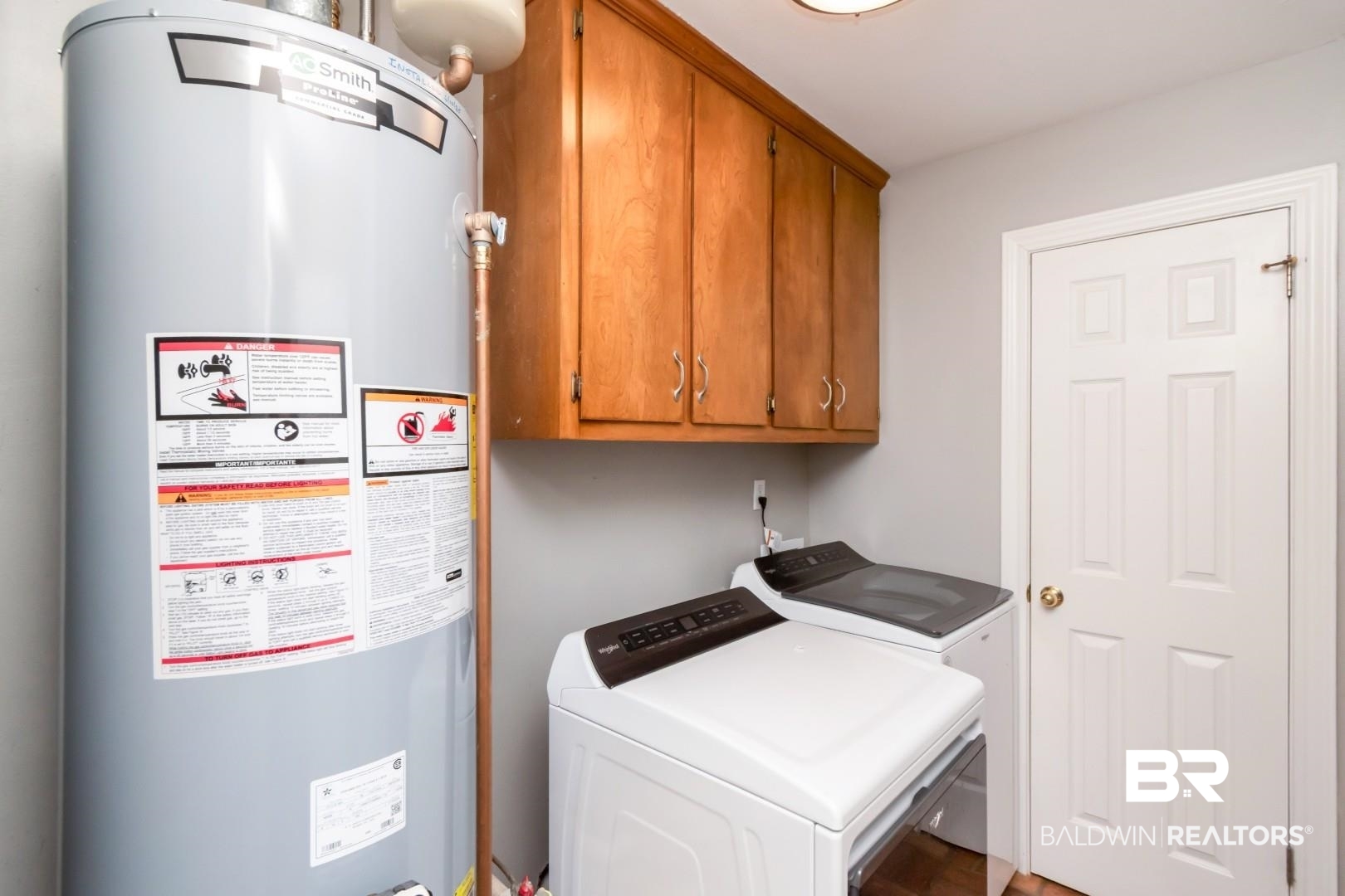 10691 Hunters Ridge Drive Mobile, AL 36695 - Photo 24 of 37 Dedicated laundry area featuring a water heater, upper cabinetry with wood-finish doors, a paneled door, and light gray walls