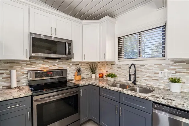 a kitchen with stainless steel appliances granite countertop a sink a stove a microwave a sink and cabinets