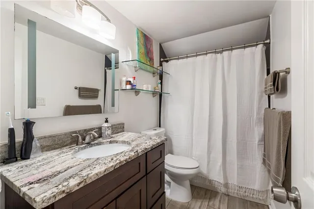a bathroom with a granite countertop sink toilet and shower